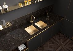 a kitchen counter with two sinks and gold faucets