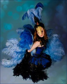 a woman dressed in blue and black with feathers on her head