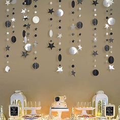 a table topped with cakes and desserts under a star filled wall hanging from the ceiling