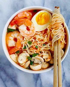 an overhead view of a bowl of noodles with shrimp, mushrooms and egg in it