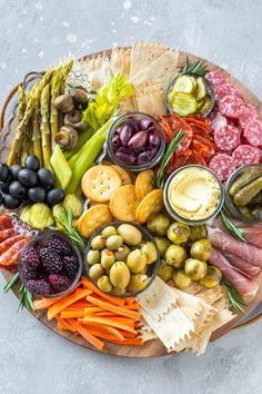 a platter filled with meats, cheeses, olives, pickles and crackers