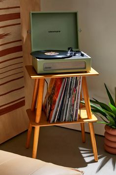 a record player sitting on top of a wooden stand next to a potted plant