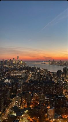 an aerial view of the city skyline at night with bright lights and water in the background