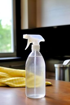 a spray bottle sitting on top of a wooden table next to a yellow towel and window