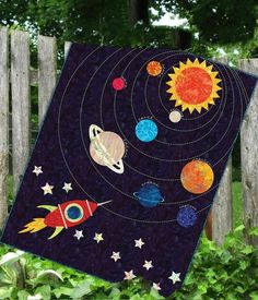 the solar system quilt is hanging on a fence