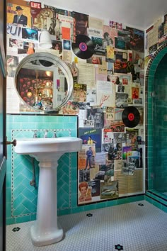 a bathroom with a sink, mirror and wall covered in records on the walls next to it