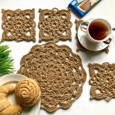 crocheted coasters and plates on a table next to a cup of tea