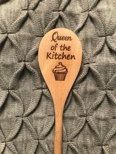 a wooden spoon with the words queen of the kitchen on it and a cupcake