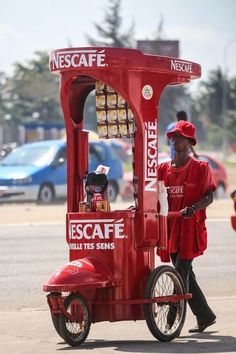 a man riding on the back of a red cart with an ice cream machine attached to it