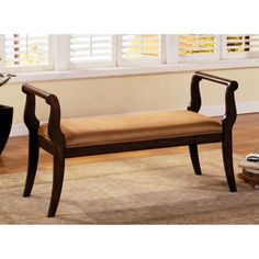 a wooden bench sitting on top of a carpeted floor next to a white window