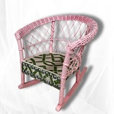 a pink wicker rocking chair with green and white patterned seat cushion on it's back