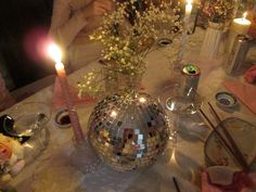 a disco ball centerpiece on a table with candles and flowers in the vases