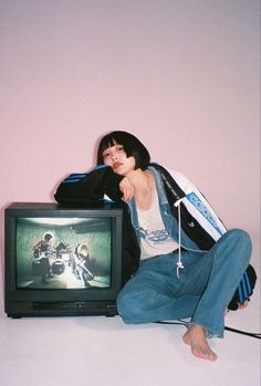 a woman sitting on the floor next to a tv