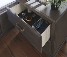 an open drawer on a table with a plant and other items