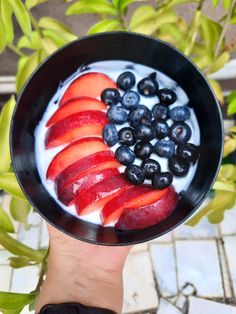 a bowl filled with fruit and yogurt on top of a tiled floor next to leaves