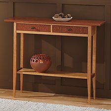 a wooden table with a vase on it and a rug in front of the table