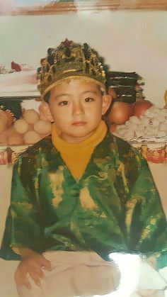 a young boy wearing a crown sitting on top of a bed in front of eggs