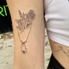 a woman with a tattoo on her arm holding a bouquet of flowers