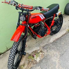 a red motorcycle parked next to a green wall