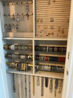 a closet filled with lots of bracelets and rings on shelves next to a door