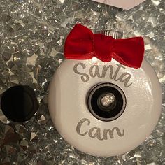 a white christmas ornament with a red bow on it that says santa can