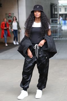 a woman with long hair wearing black pants and a hat