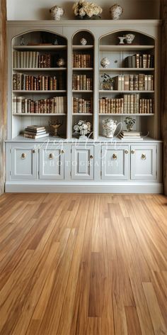 an empty room with wooden floors and white bookcases filled with lots of books