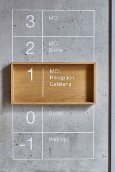 a wooden shelf sitting on top of a cement floor next to numbers and words written in different languages