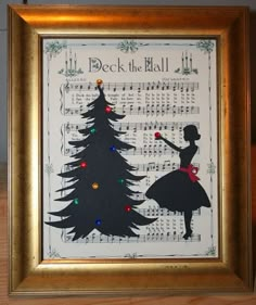 a framed christmas card with a silhouette of a woman in front of a tree and sheet music