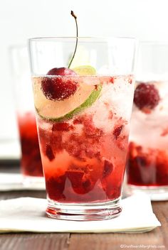 two glasses filled with fruit and ice on top of a wooden table