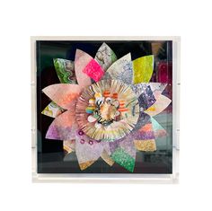 a multicolored paper art piece in a clear frame on a white background with the image of a sunflower