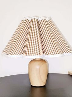 a wooden table with a brown and white checkered lamp shade on top of it