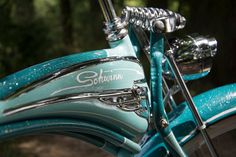 the front end of a blue bike with chrome spokes