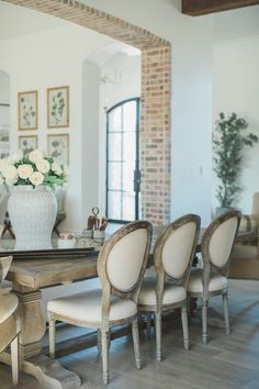 a dining room table with chairs and a vase filled with flowers