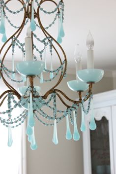 a chandelier with blue glass drops hanging from it's arms and two candles in the middle