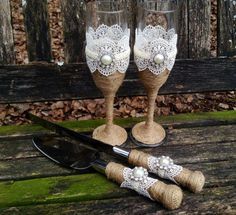 two wine glasses decorated with lace and pearls are sitting on a wooden table next to a pair of scissors