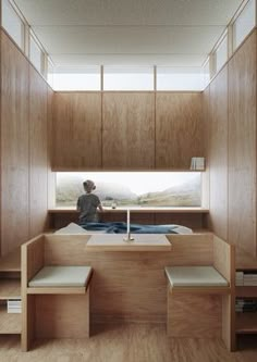 a person sitting on a bed in a room with wooden walls and shelves around them