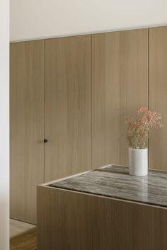 a vase filled with flowers sitting on top of a wooden counter next to a wall