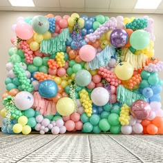 an arrangement of balloons and streamers are arranged on the floor in front of a wall