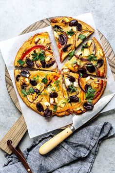 a pizza sitting on top of a wooden cutting board next to a knife and fork