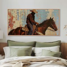 a painting of a cowboy riding a horse on a wall above a bed with pillows