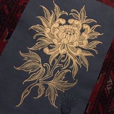 a blue book with gold designs on it sitting on a red rug next to a pineapple