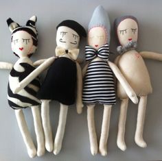 three dolls are laying next to each other on the floor, one is wearing a black and white striped dress