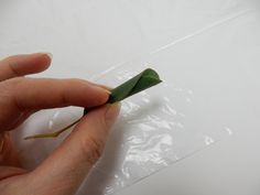 a person is holding a piece of green material in their left hand and the other hand is pulling it up