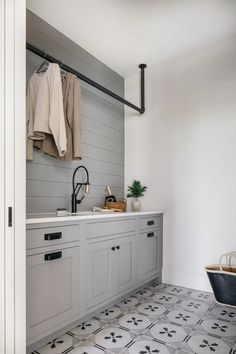 a kitchen with grey cabinets and white counter tops, an open door leading to the laundry room