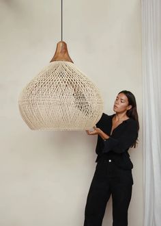 a woman is holding up a light fixture