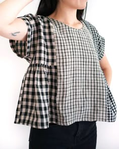 a woman wearing a black and white checkered top with her hand on her head