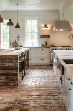 a kitchen with white cabinets and wooden floors is pictured in this image, there are several lights hanging from the ceiling