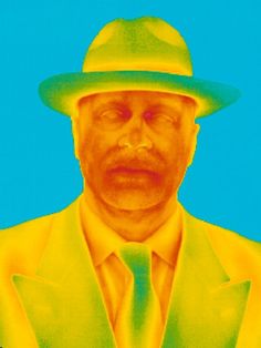 a man in a yellow suit and green hat is looking at the camera with an intense look on his face