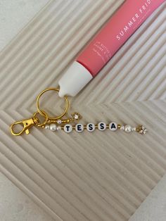 a keychain with a tube of lip balm on it next to a bottle of lipstick